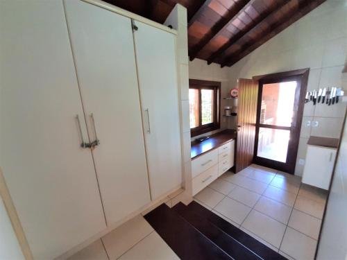 a large kitchen with white cabinets and a window at 3Suítes, piscina e vista do mar em condomínio pé na areia - pátio compartilhado in Búzios