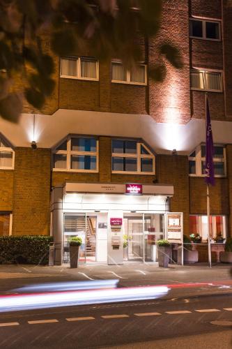 a building on a street at night with a car at Mercure Hotel Duisburg City in Duisburg