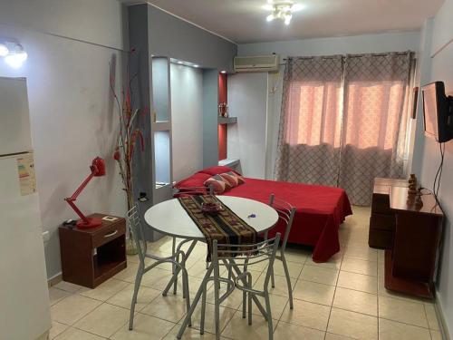 Zimmer mit einem Tisch und einem Bett mit einer roten Decke in der Unterkunft MONOAMBIENTE CENTRICO AMOBLADO in San Juan