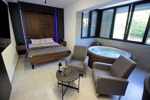 a bedroom with a tub and a bed and chairs at Jacuzzi Sauna SelfCheckIn Mystic in Mostar
