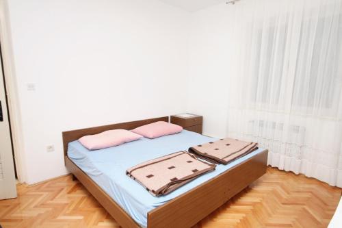 una camera con un letto con due cuscini rosa di Apartments by the sea Supetar, Brac - 6040 a Supetar (San Pietro di Brazza)