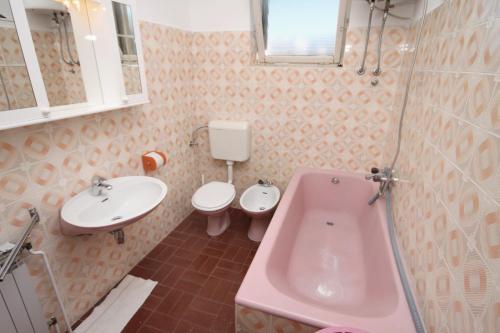 un bagno rosa con lavandino e servizi igienici di Apartments by the sea Supetar, Brac - 6040 a Supetar (San Pietro di Brazza)