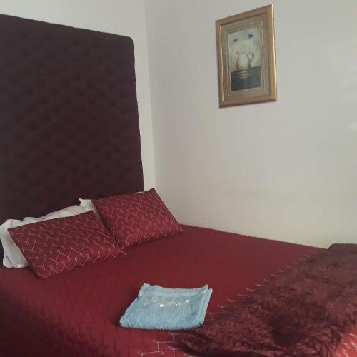 a bed with a red comforter and two pillows at Casa dragão in Porto