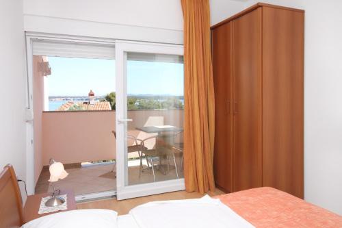 a bedroom with a bed and a balcony with a table at Apartment Tkon 6215c in Tkon