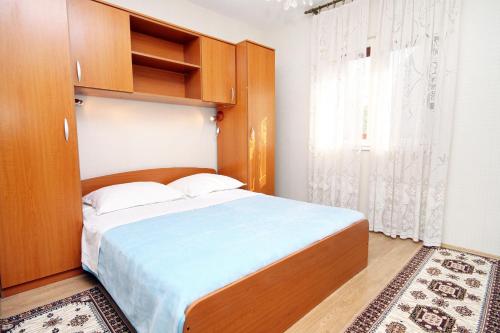 1 dormitorio con 1 cama grande y cabecero de madera en Apartments by the sea Arbanija, Ciovo - 6062, en Trogir