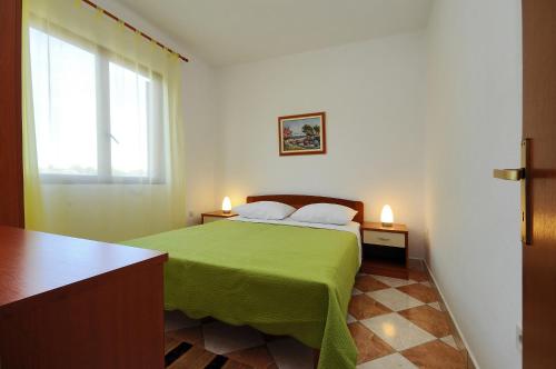 um quarto com uma cama verde e uma janela em Seaside apartments with a swimming pool Nin, Zadar - 6153 em Nin