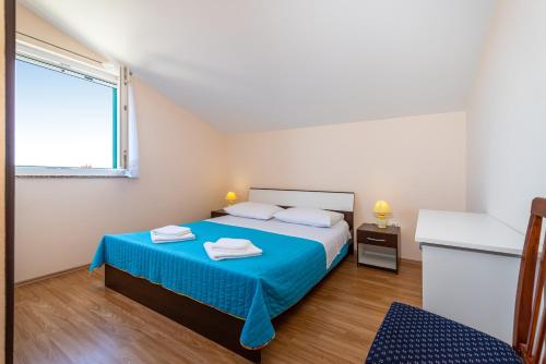een slaapkamer met een bed met blauwe lakens en een raam bij Seaside apartments with a swimming pool Posedarje, Novigrad - 6162 in Posedarje