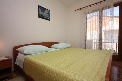a bedroom with a bed with a yellow comforter and a window at Apartments with parking space Turanj, Biograd - 6212 in Turanj