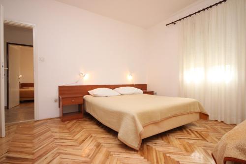 een slaapkamer met een bed en een houten vloer bij Apartments with a parking space Ljubac, Zadar - 6141 in Ražanac