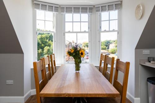 a dining room table with a vase of flowers on it at Caddyshacks Gullane, 4 bedroom, 4 bath, Golf, Beach in Gullane