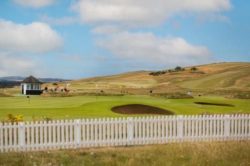 a white fence on a golf course with a hill at Caddyshacks Gullane, 4 bedroom, 4 bath, Golf, Beach in Gullane