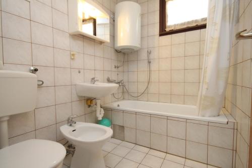 a bathroom with a toilet and a sink and a bath tub at Apartment Banjole 7487a in Banjole