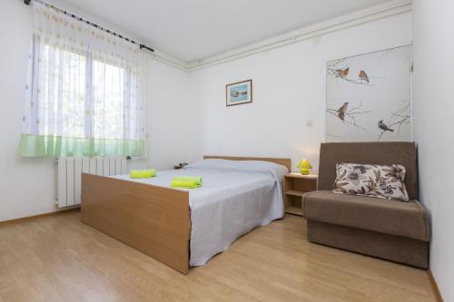 a bedroom with a bed and a chair at Apartment Vinez 7471a in Labin