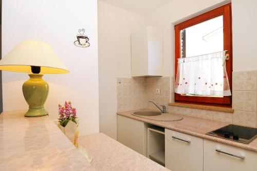 a kitchen with a table with a lamp and a sink at Apartments with a parking space Ravni, Labin - 7450 in Ravni