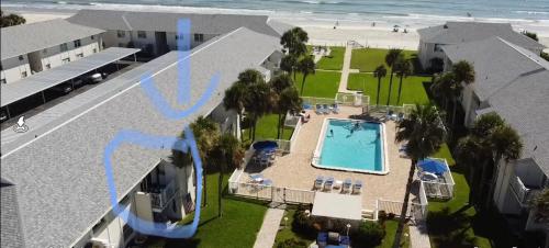 an aerial view of a resort with a swimming pool and the beach at Beachfront Serenity Private Balcony with Ocean View, Shared Heated Pool and BBQ in New Smyrna Beach