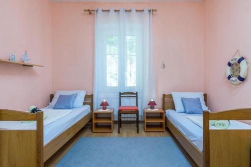 a bedroom with two beds and a window and a chair at Seaside holiday house Plomin Luka, Labin - 7466 in Plomin