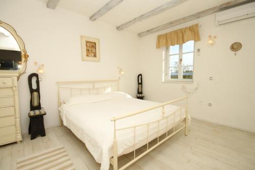 a white bedroom with a white bed and a window at Family friendly house with a swimming pool Skrapi, Central Istria - Sredisnja Istra - 7526 in Brajkovići