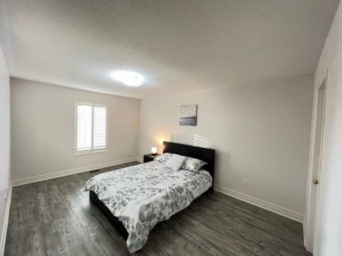 een witte slaapkamer met een bed en een raam bij Beautiful Vacation Home near Toronto Airport in Mississauga