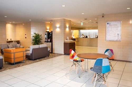 einen Wartebereich mit einem Tisch und Stühlen in der Lobby in der Unterkunft Court Hotel Mito in Mito