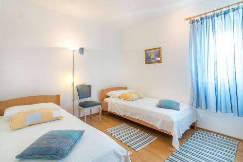 a bedroom with two beds and a chair and a window at Apartment Arbanija 7543a in Trogir