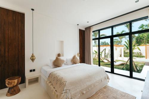 a bedroom with a white bed and a large window at Villa Lamer Canggu in Canggu