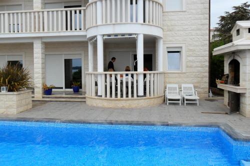 uma casa com piscina em frente a uma casa em Family friendly apartments with a swimming pool Rogoznica - 7557 em Rogoznica