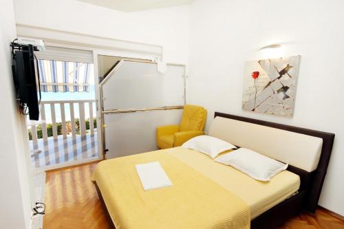1 dormitorio pequeño con 1 cama y 1 silla amarilla en Family friendly apartments with a swimming pool Rogoznica - 7557, en Rogoznica