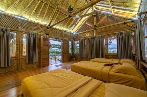 a bedroom with two beds in a room with windows at Catappa Village Lombok in Sekotong