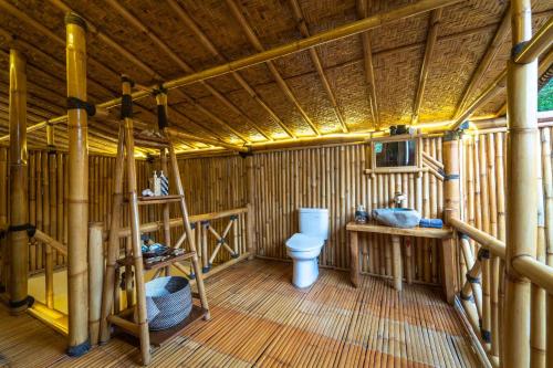 a wooden bathroom with a toilet and a sink at Catappa Village Lombok in Sekotong