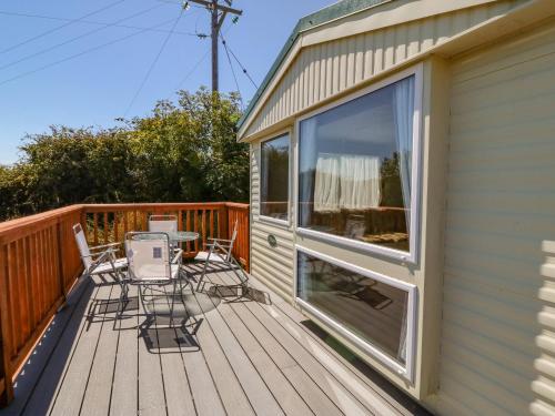 a patio with chairs and a table on a deck at Gorphwysfa Caravan in Cemaes Bay