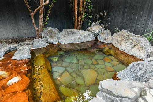 a pool of water with rocks in a garden at Ryokan Yayanoyu in Ueki