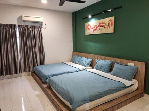 a bed in a bedroom with a green wall at Homestay 116 in Ipoh