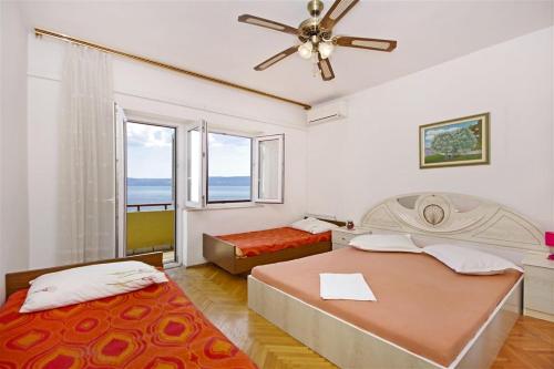 1 Schlafzimmer mit 2 Betten und einem Deckenventilator in der Unterkunft Apartments by the sea Dugi Rat, Omis - 7575 in Dugi Rat