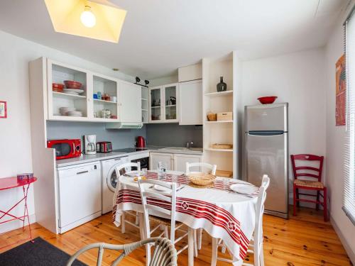une cuisine avec une table, des chaises et un réfrigérateur dans l'établissement Charmant appartement au centre-ville de Saint-Jean-de-Luz, plage et commerces à proximité - FR-1-4-651, à Saint-Jean-de-Luz