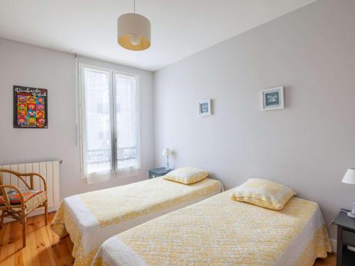une chambre avec deux lits et une chaise et une fenêtre dans l'établissement Charmant appartement au centre-ville de Saint-Jean-de-Luz, plage et commerces à proximité - FR-1-4-651, à Saint-Jean-de-Luz