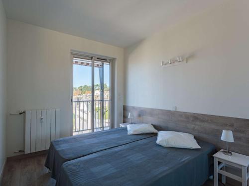 1 dormitorio con cama azul y ventana grande en Appartement Saint-Jean-de-Luz, 2 pièces, 4 personnes - FR-1-4-655, en San Juan de Luz