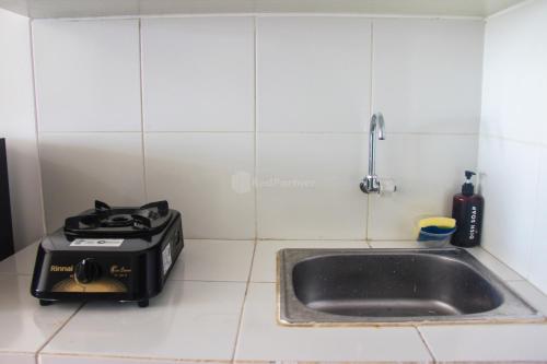 a kitchen counter with a sink and a stove at RedLiving Apartemen Gunung Putri Square - Abidin Room Tower Pinus in Parungtandjung
