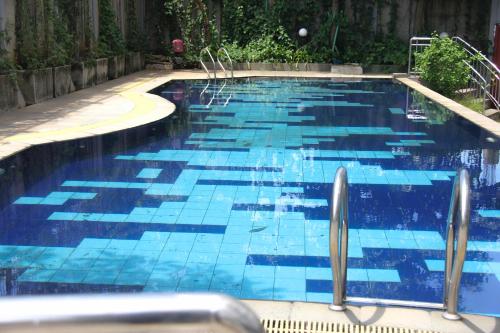 una piscina azul con azulejos azules. en RedLiving Apartemen Gunung Putri Square - Abidin Room Tower Pinus, en Parungtandjung
