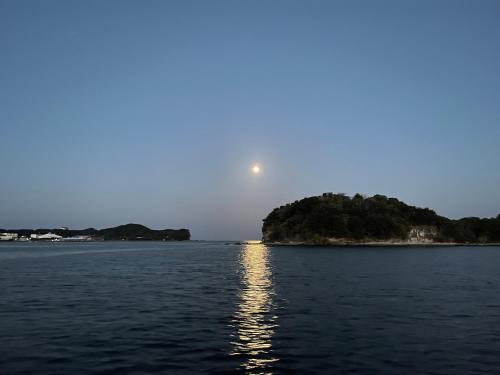 a moon rising over a body of water at 白浜貸別荘2-76 in Kanayama