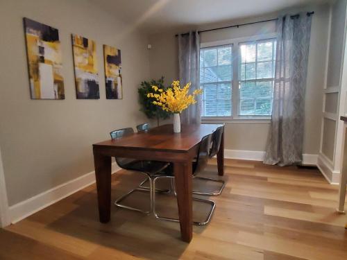 a dining room table with chairs and a vase of flowers on it at Cheerful 2 BR Near Colleges, Downtown, Attractions in Montgomery