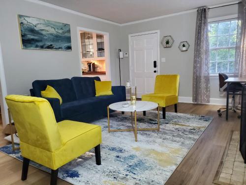 a living room with a blue couch and two yellow chairs at Cheerful 2 BR Near Colleges, Downtown, Attractions in Montgomery