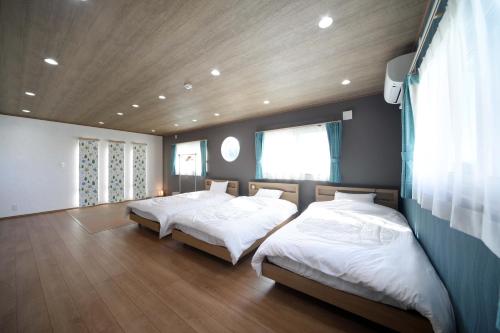 a bedroom with two beds and a wooden ceiling at 白浜貸別荘2-79 in Shirahama