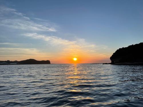 a sunset on a body of water with the sun setting at 白浜貸別荘2-79 in Shirahama
