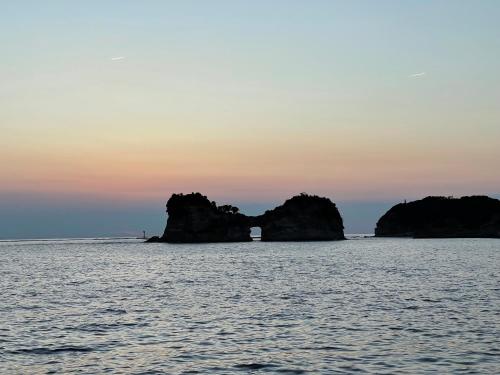 a group of rocks in the ocean at sunset at 白浜貸別荘2-79 in Shirahama