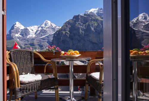 a dining room table with a view of a mountain range at Eiger Guesthouse in Mürren