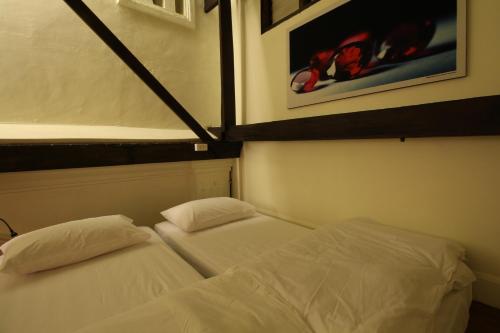 two beds in a room with white sheets at Baan Luang Rajamaitri Historic Inn in Chanthaburi