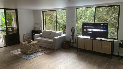 a living room with a white couch and a television at Loft Mágico en Nativa Resort in Tarcoles