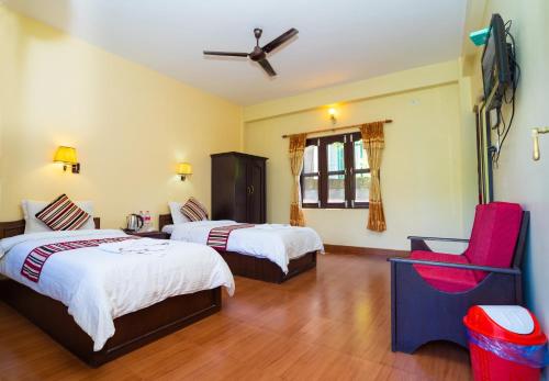 una habitación de hotel con 2 camas y una silla roja en Butterfly Lodge, en Pokhara