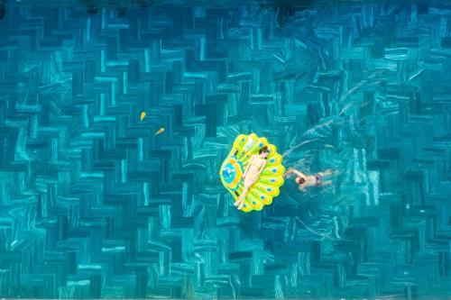 a person floating on a surfboard in a swimming pool at Mai Phuong Resort Phu Quoc in Phú Quốc