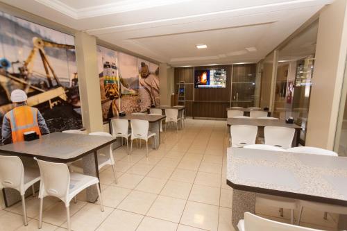 a dining room with tables and white chairs at HOTEL EXECUTIVO in Parauapebas